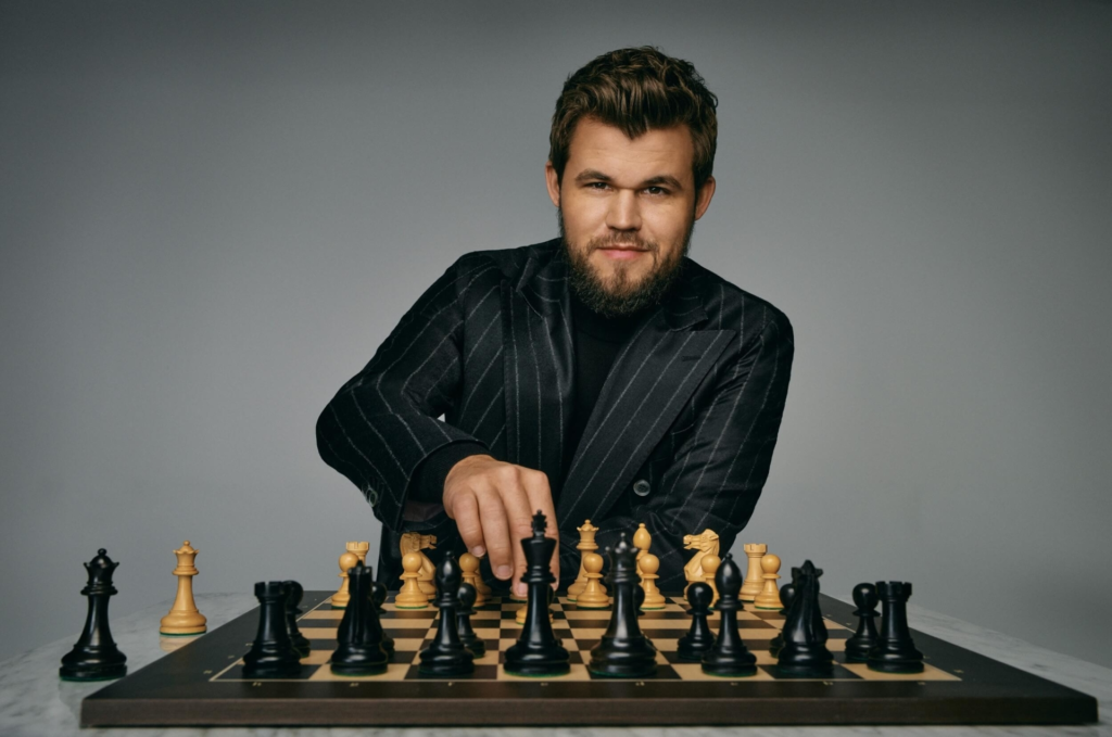 A photo of Magnus Carlsen relaxing outdoors, perhaps playing a different game or enjoying a hobby. He should look calm and content.