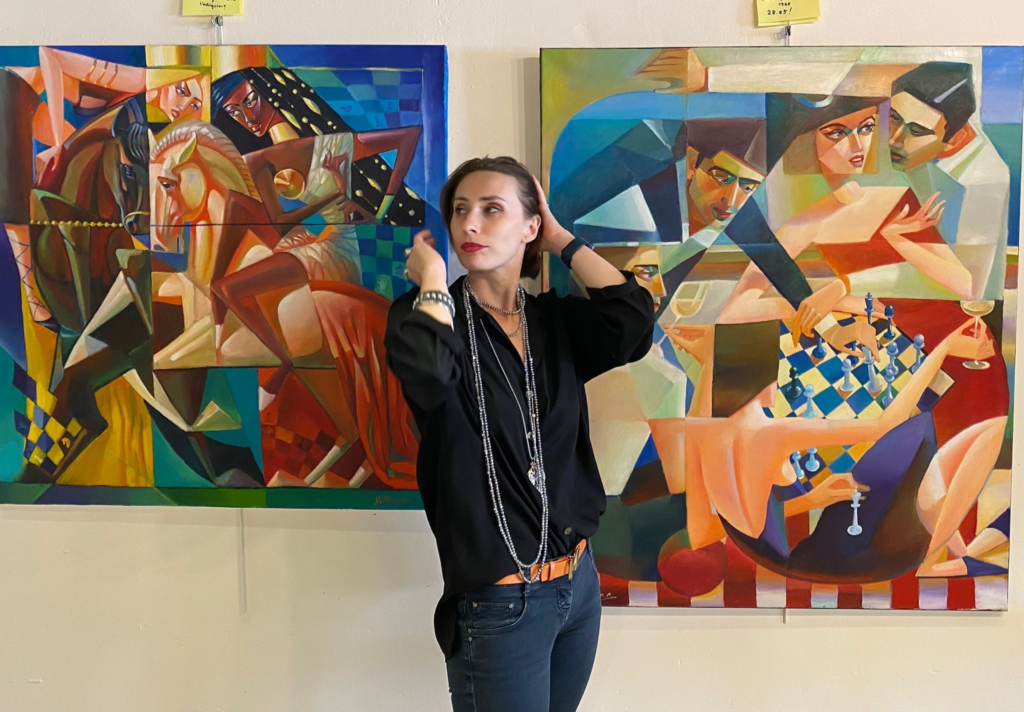 WFM Maria Yugina in front of two of her chess paintings.